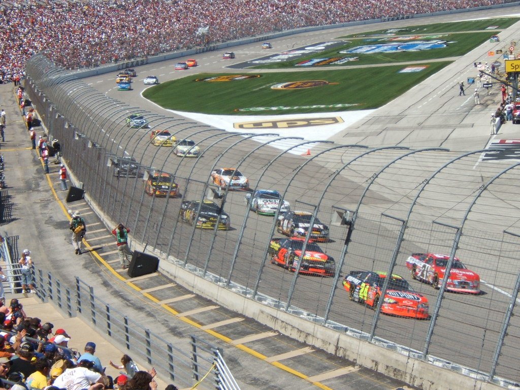 NASCAR cars driving around a corner during race. 