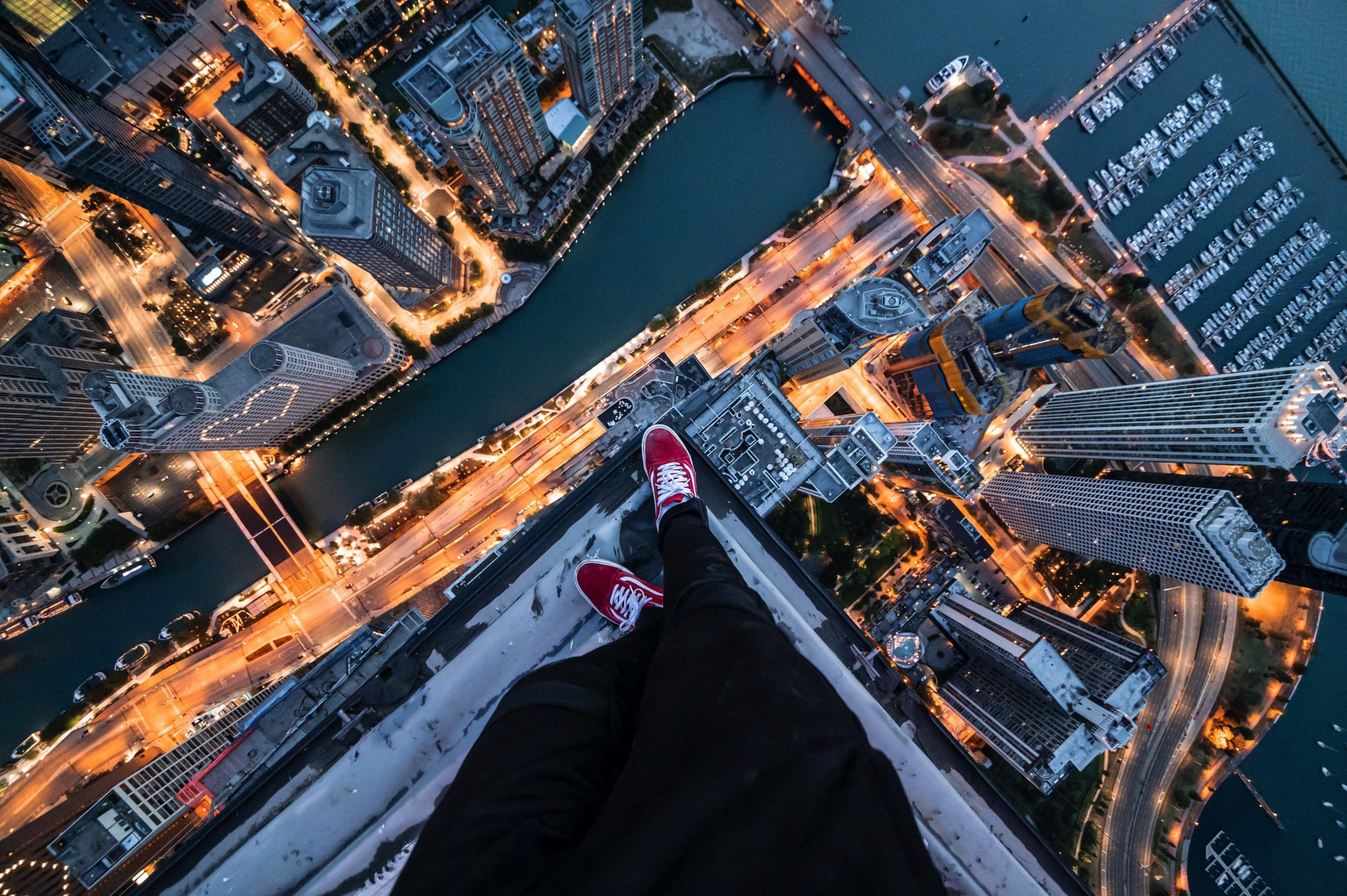 Photograph of a man wearing red vans standing on top of a skyscraper