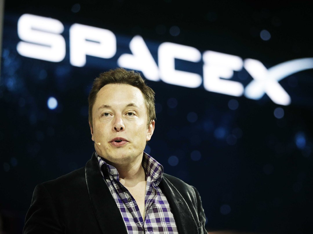 elon musk speaking in front of a space x sign