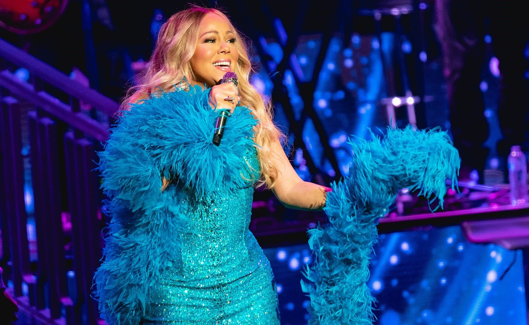 Mariah Carey performing at a concert wearing a blue dress