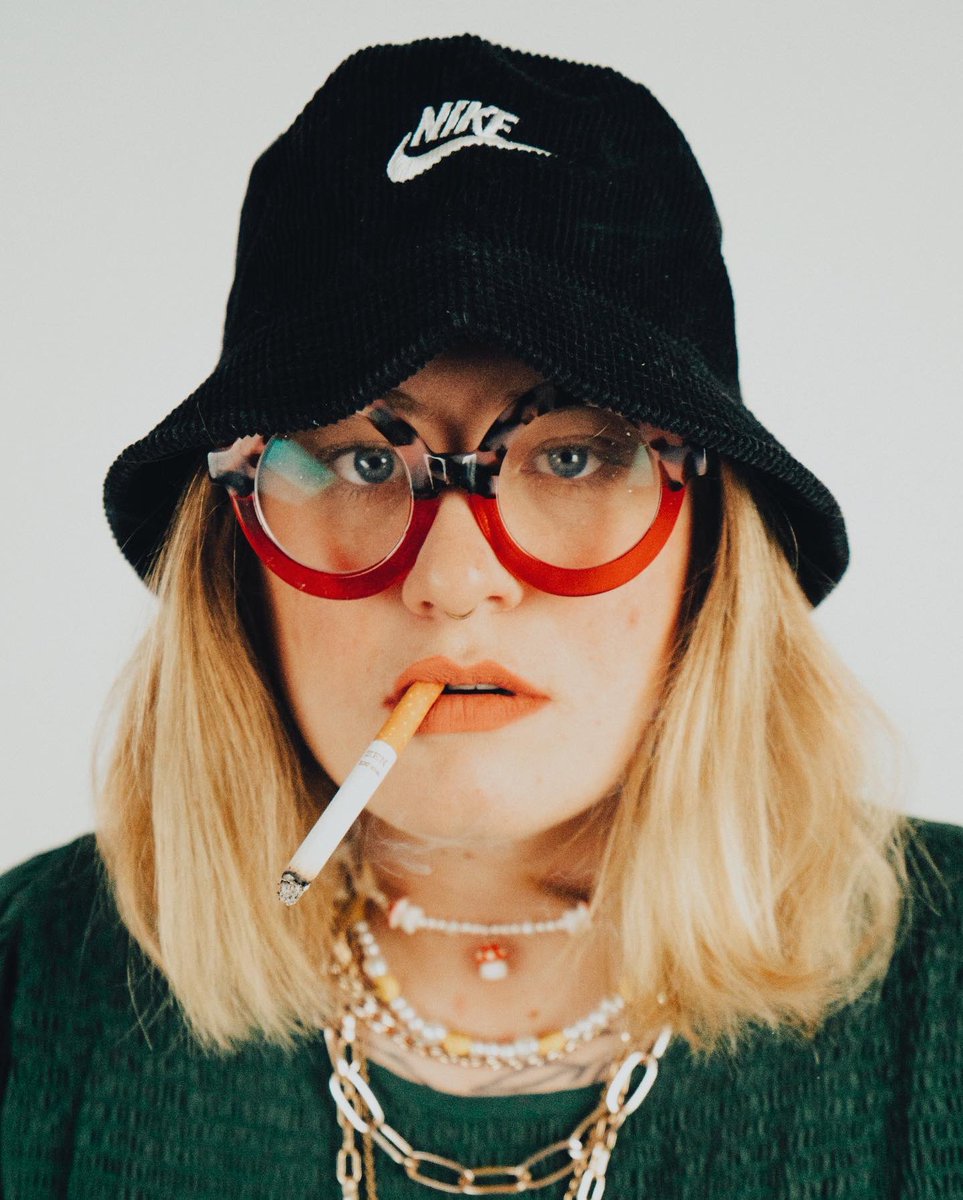 Artist Stacie A Buhler with a cigarette between her lips ad a Nike cap