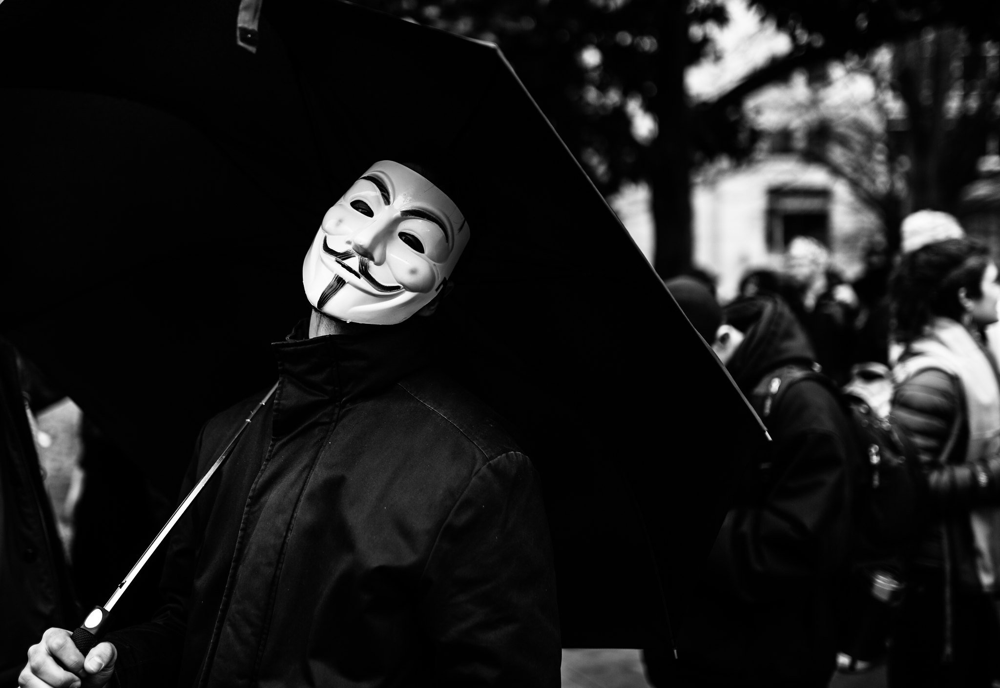A person wears a mask associated with anonymous, who popularized the term doxxing