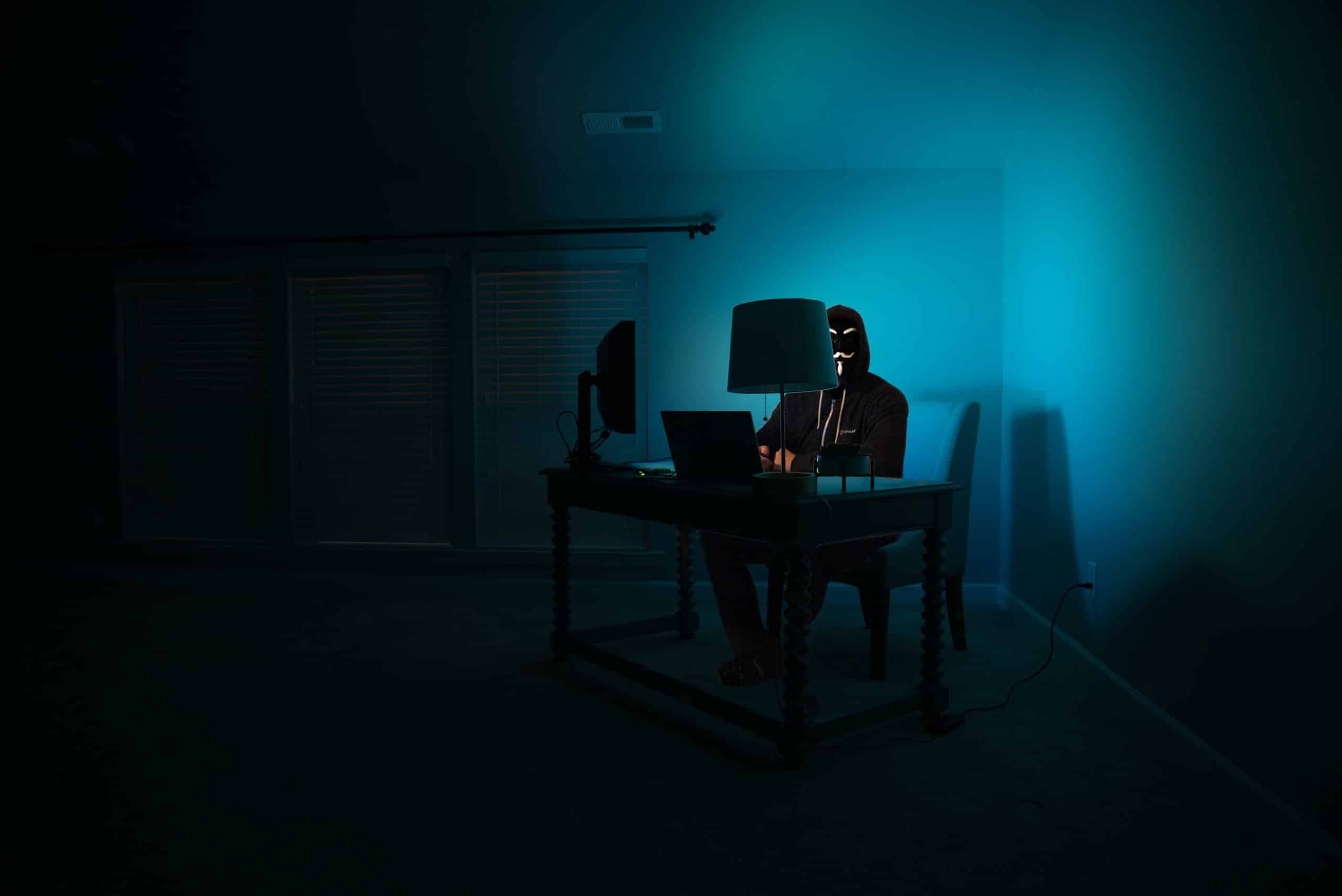 image of man in dark room sat at computer