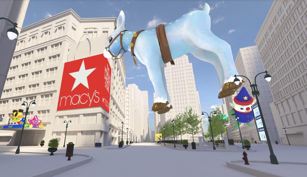 macy's thanksgiving metaverse : There is a float of a blue reindeer in front of a virtual representation of the Macy's store in downtown New York. 