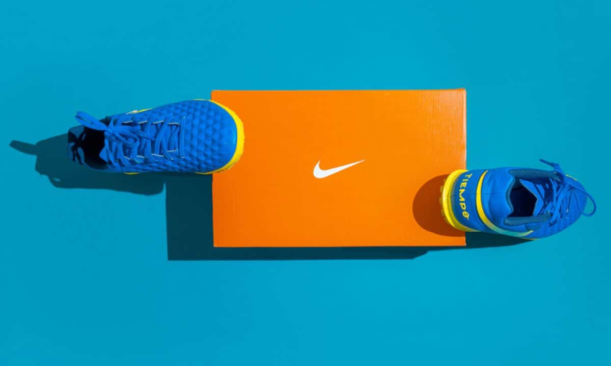 A pair of Nike sneakers and the Nike logo against a blue background.