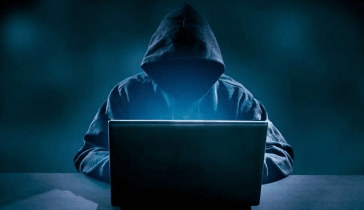 stock image of hooded figure looking on computer