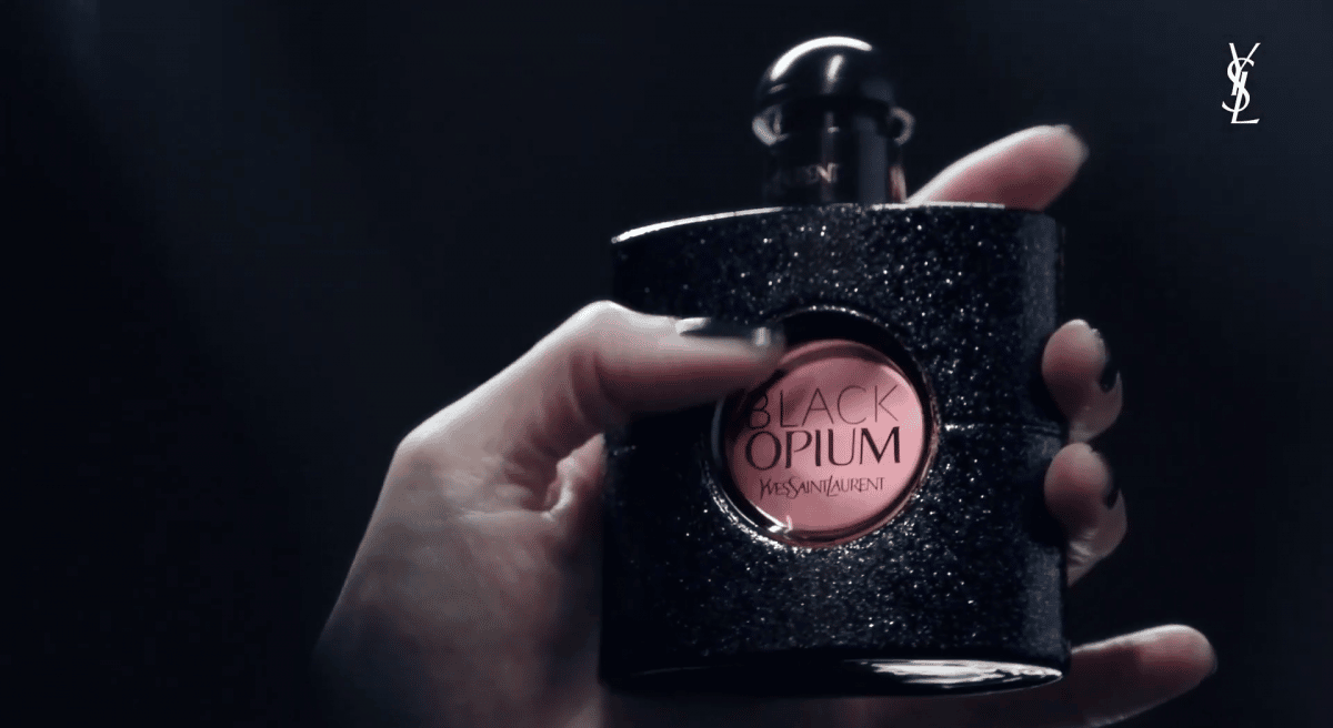 a person holding an Yves Saint Laurent "Black Opium" fragrance, for which the latest NFT campaign is set to launch.