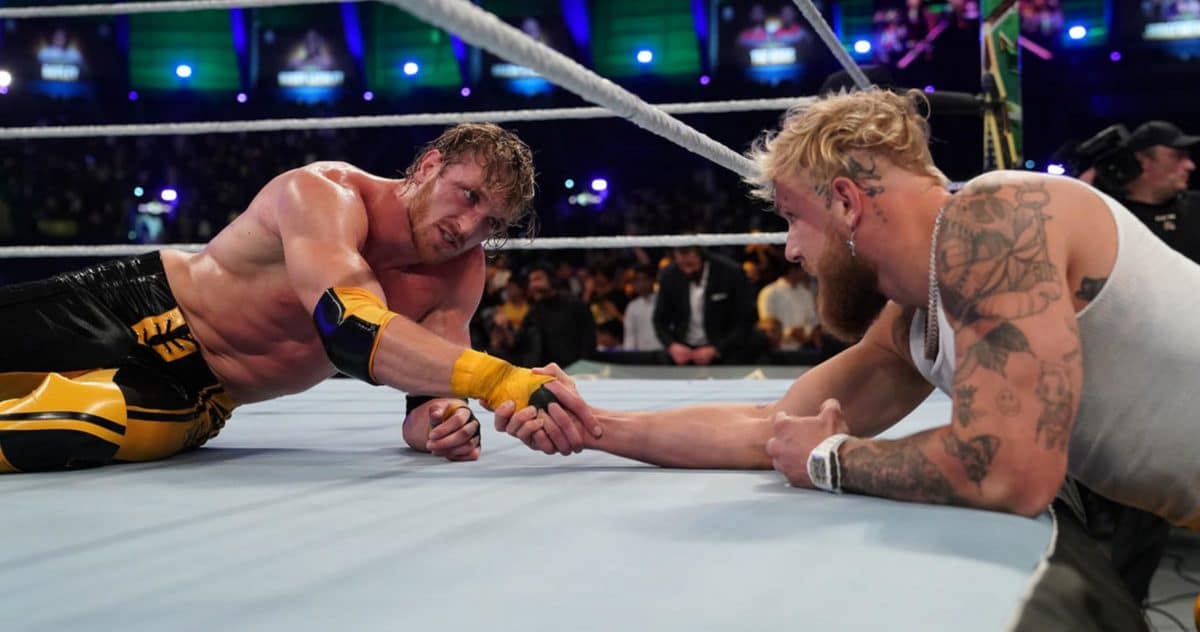 Logan Paul and his brother Jake Paul are seen holding hands during a wrestling match.