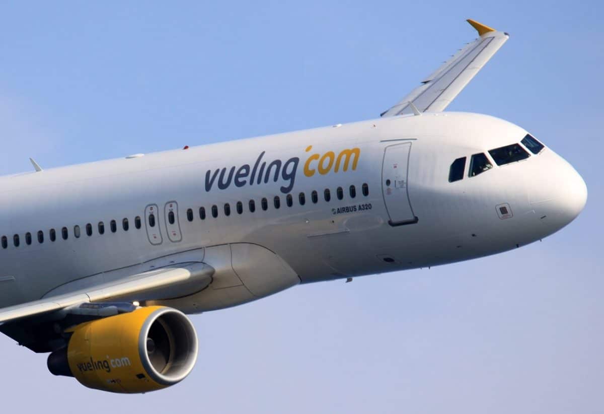 A jet is seen flying through blue skies in support of Vueling Crypto payments.