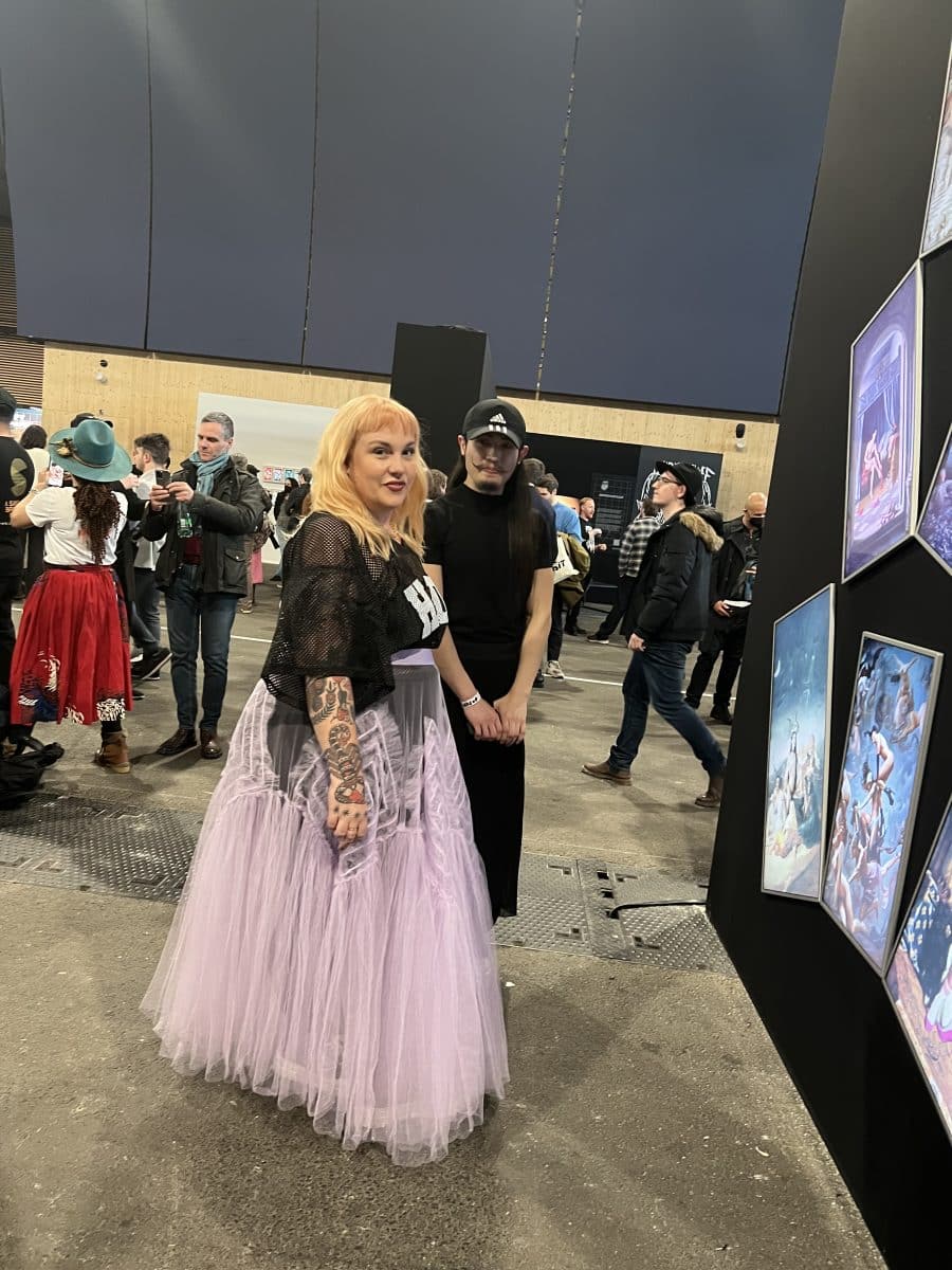 Two people Betty, CEO of Deadfellaz (In black top and long stiletto skirt), and artist YuYu (dressed in all black) looking at an art installation