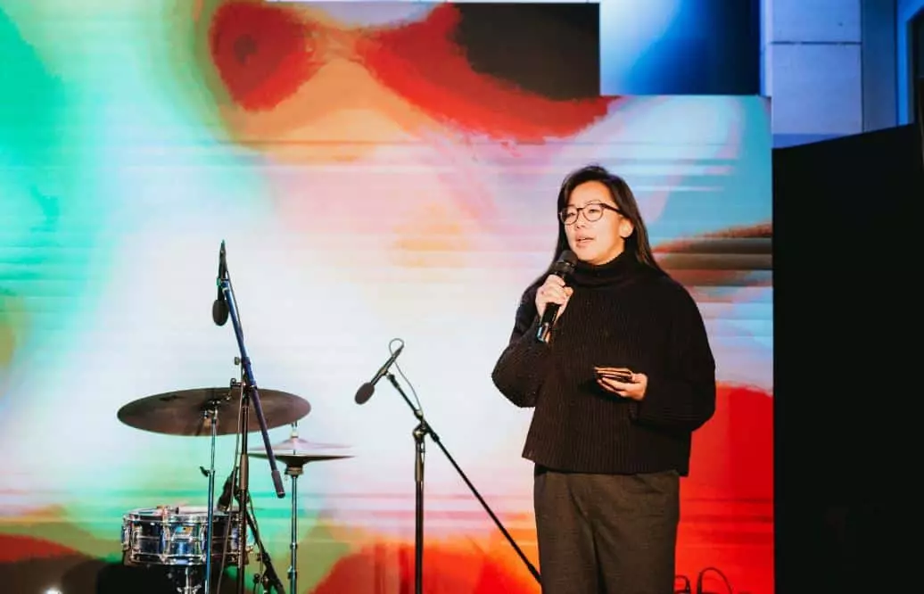 image of NFT literature artist Kalen Iwamoto speaking at a microphone on stage