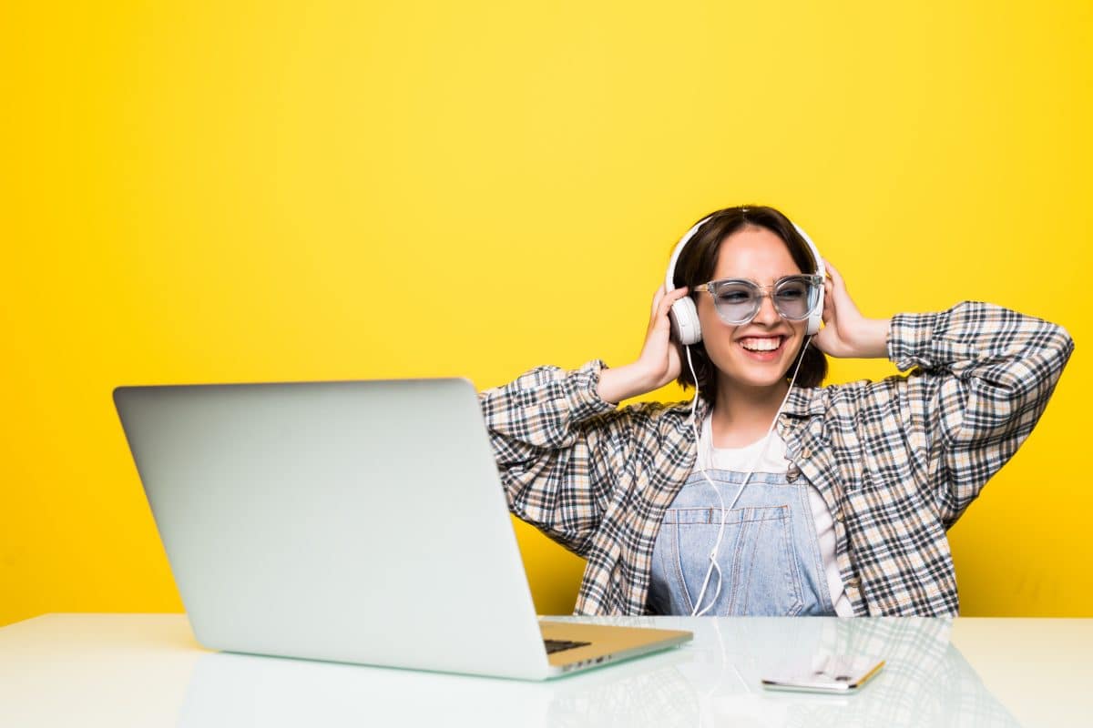 image of ahappy woman listening to music in headphones on a yellow background