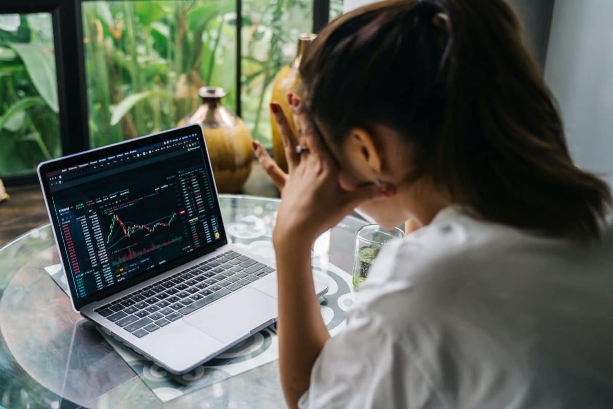 image of a woman looking at a computer screen seeing a stock price plummet to represent a rug pull 
