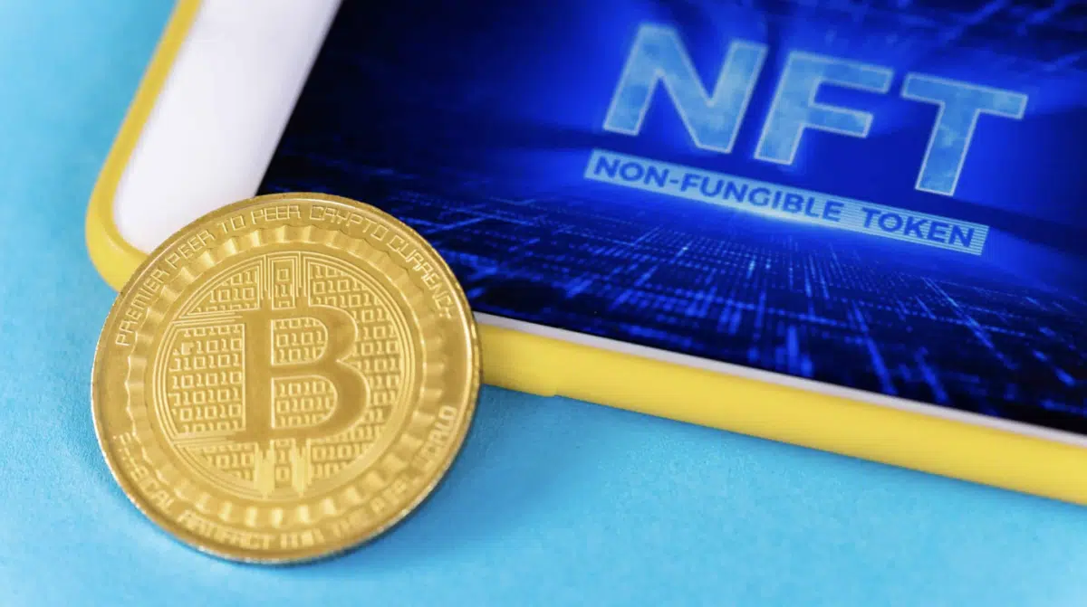 An illustration showing a Bitcoin and a tablet with NFTs on it. 