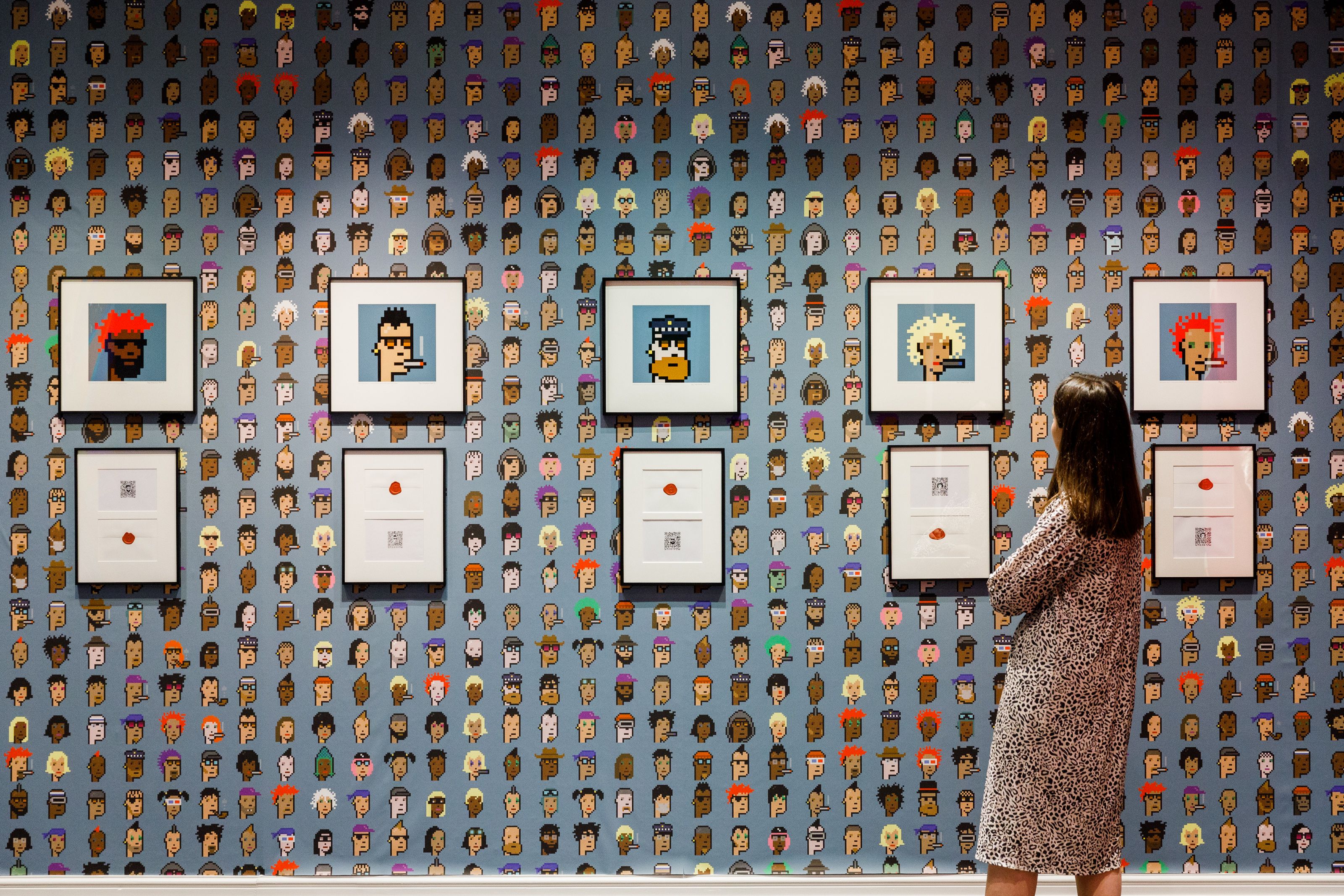 image of a woman looking at five CryptoPunks NFTs from Sotheby's