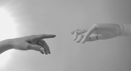 image of a human reaching out touching a robot hand to signify ai chatbot