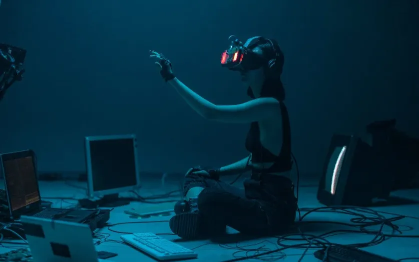 A person sitting on the floor and using a VR headset to participate in the metaverse
